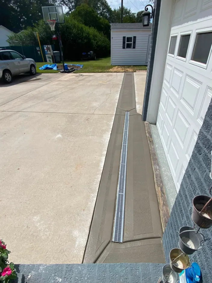 Channel drain set into concrete beside a garage